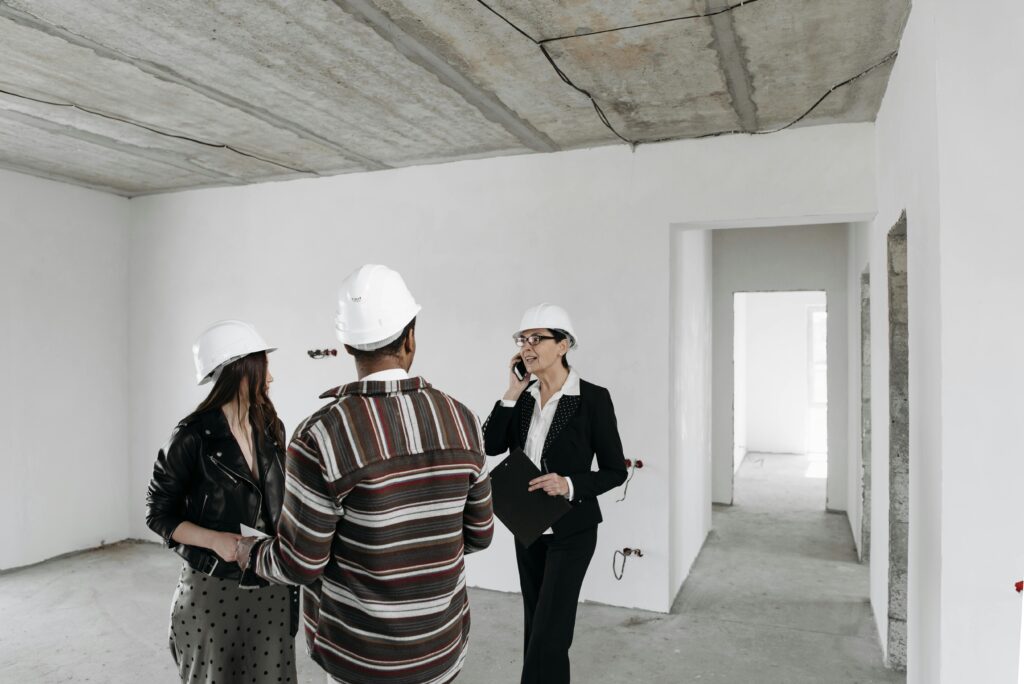 Two home buyers with a construction manager walking through a home under construction
