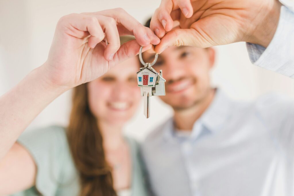 A young couple, smiling and holding the keys to their new home